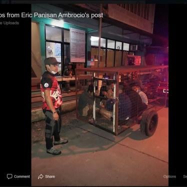 A screenshot of an officer with five youths locked inside a dog cage after breaking curfew in Laguna province, the Philippines on March 20, 2020. © 2020 Facebook