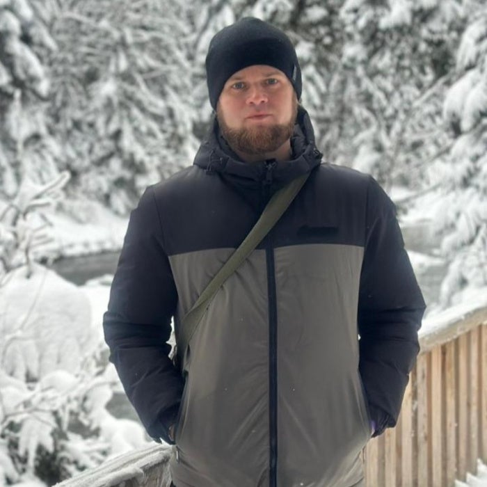 A man poses for a photo standing outside